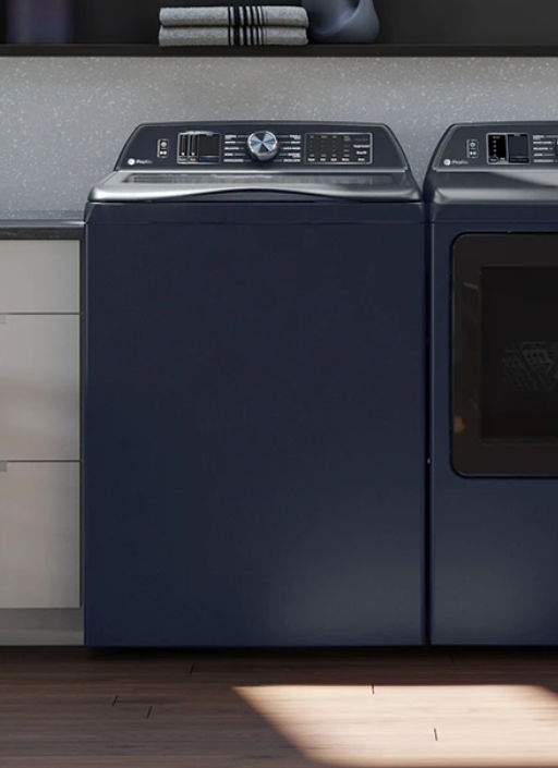 A navy washing machine and dryer in a modern laundry room.