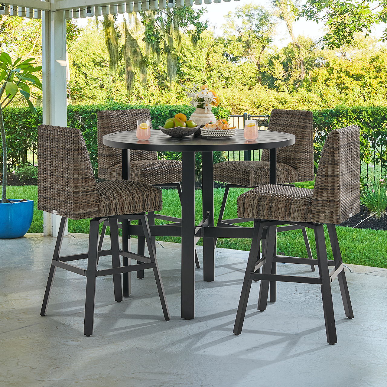 Outdoor dining set with four wicker chairs and a round table.