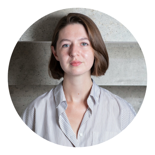 A woman with short hair, wearing a striped shirt, stands against a textured background.