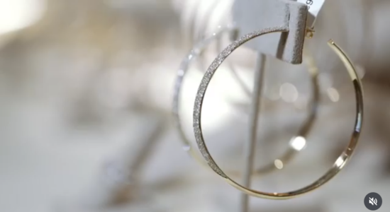 Gold hoop earrings displayed on a stand.