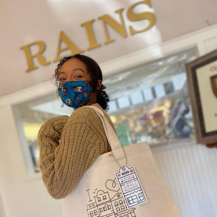 Shopper with canvas bag in front of RAINS.