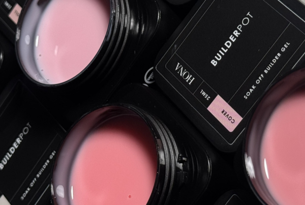 Containers of pink nail gel with black labels scattered on a surface.
