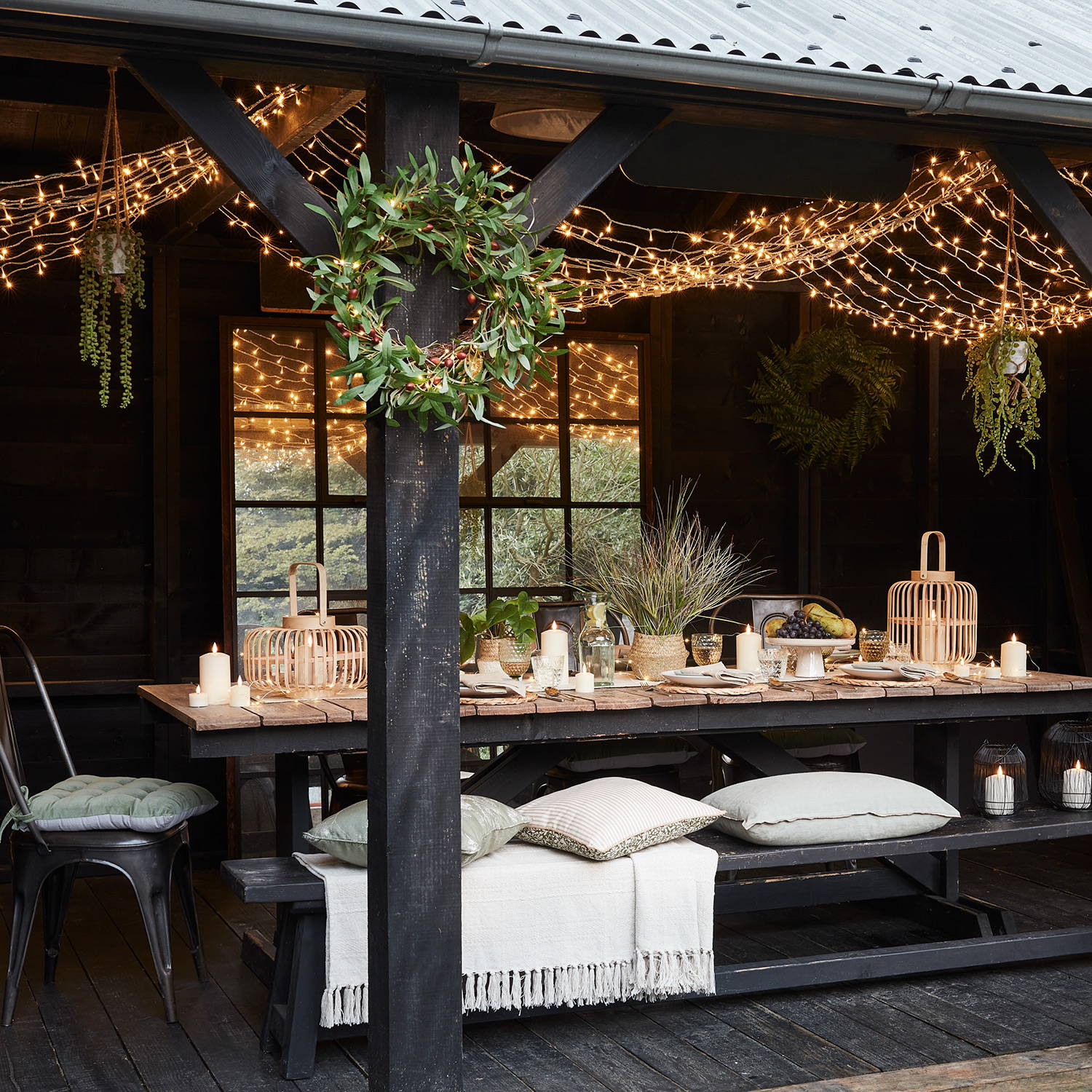 Outdoor living, dining table with a ceiling of fairy lights, lanterns and candles