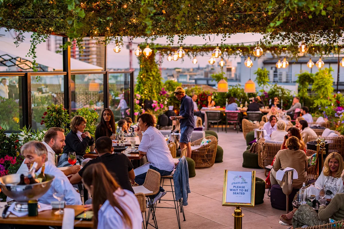 Busy restaurant rooftop patio with commercial outdoor dining furniture, guests, and flexible seating arrangements 