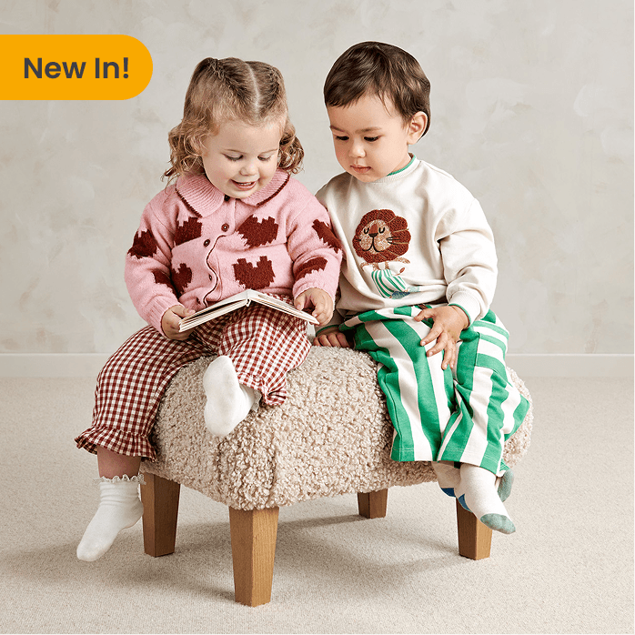 Two children reading on a fluffy stool in a cozy setting.