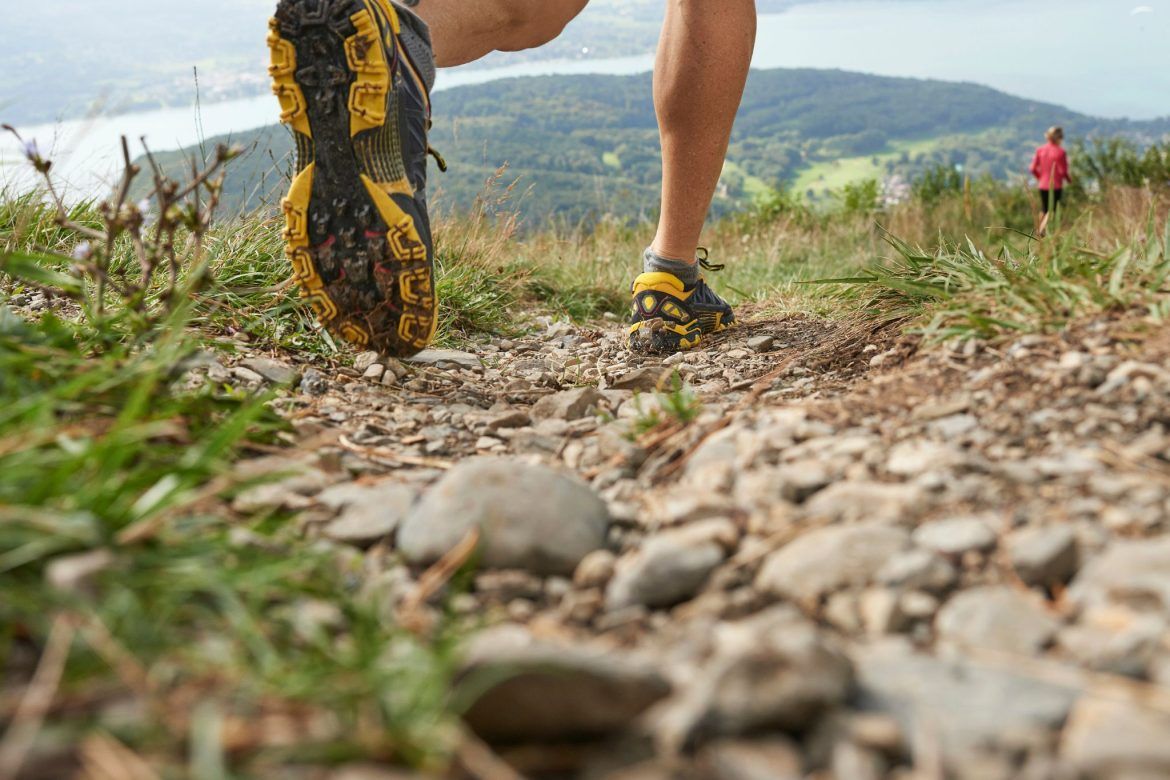 A close-up of a runner's foot on a rocky trail.