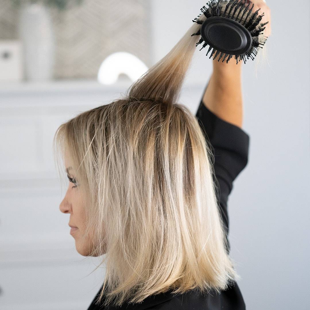 Blonde woman creating volume at the root with Blow Brush