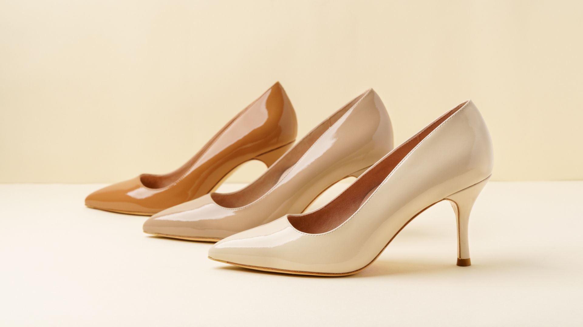 Three pairs of stylish high-heeled shoes in neutral tones.