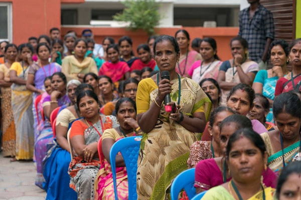 Female fair trade worker with microphone during meeting.