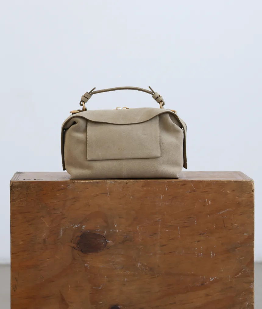 A small beige handbag on a wooden surface.