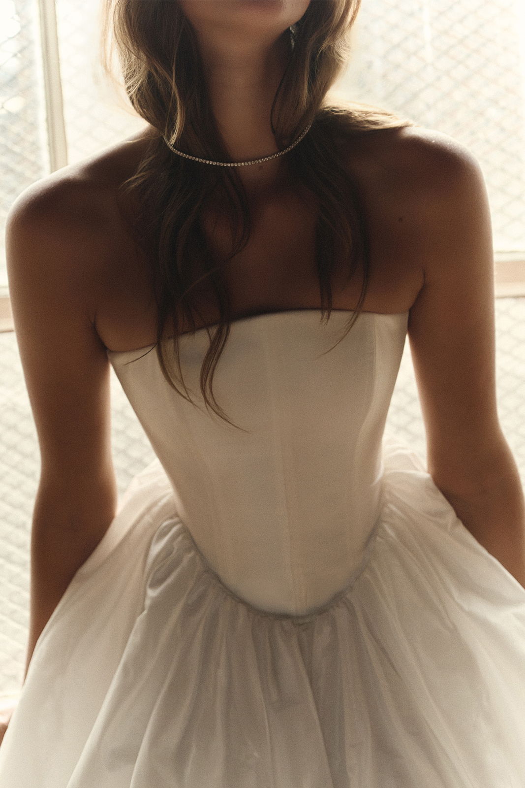 Woman in a strapless white dress with a tulle skirt.