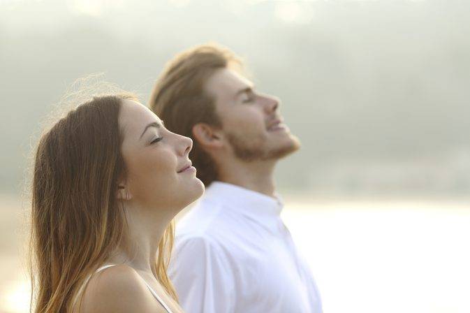 Man and woman with eyes closed head tilted back, smiling and breathing. 