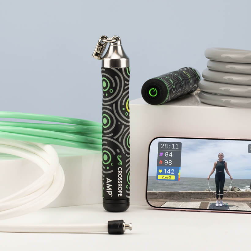 Fitness equipment including a Crossrope AMP handles and jump ropes and smartphone displaying workout video.