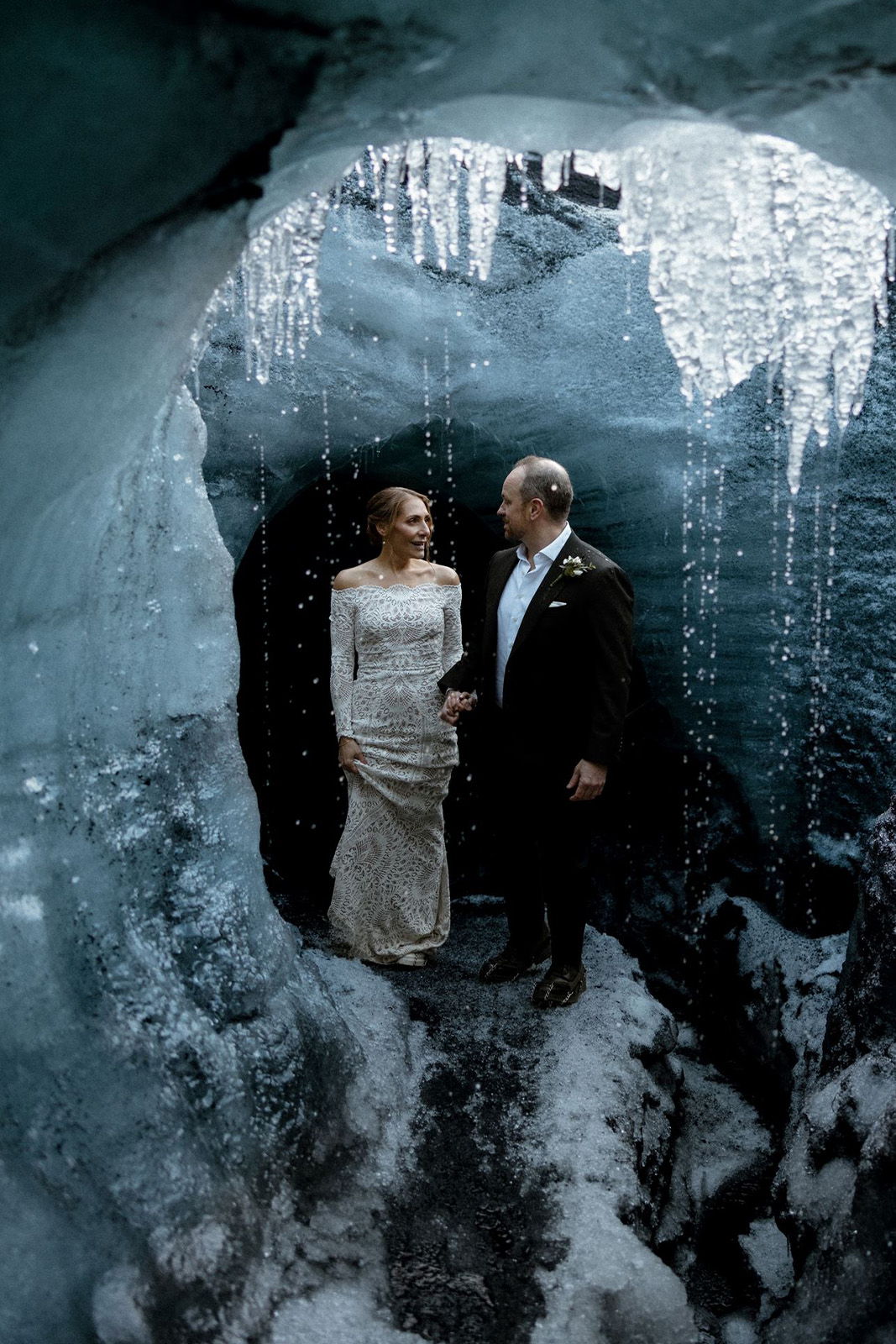 A couple in formal attire standing in an ice cave.
