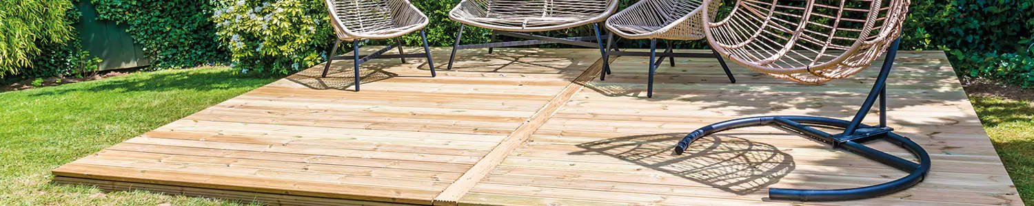 An image of some timber decking with four different garden chairs being placed on top of them. 