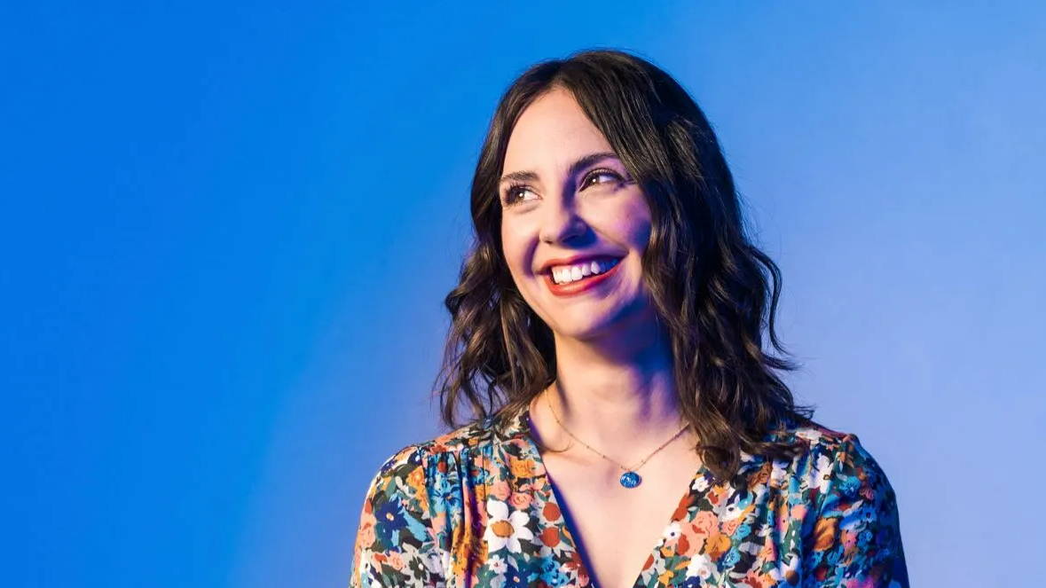 Jalene poses for a portrait in front of a blue background, looking off to the viewer's left - Top 40 Under 40 2021