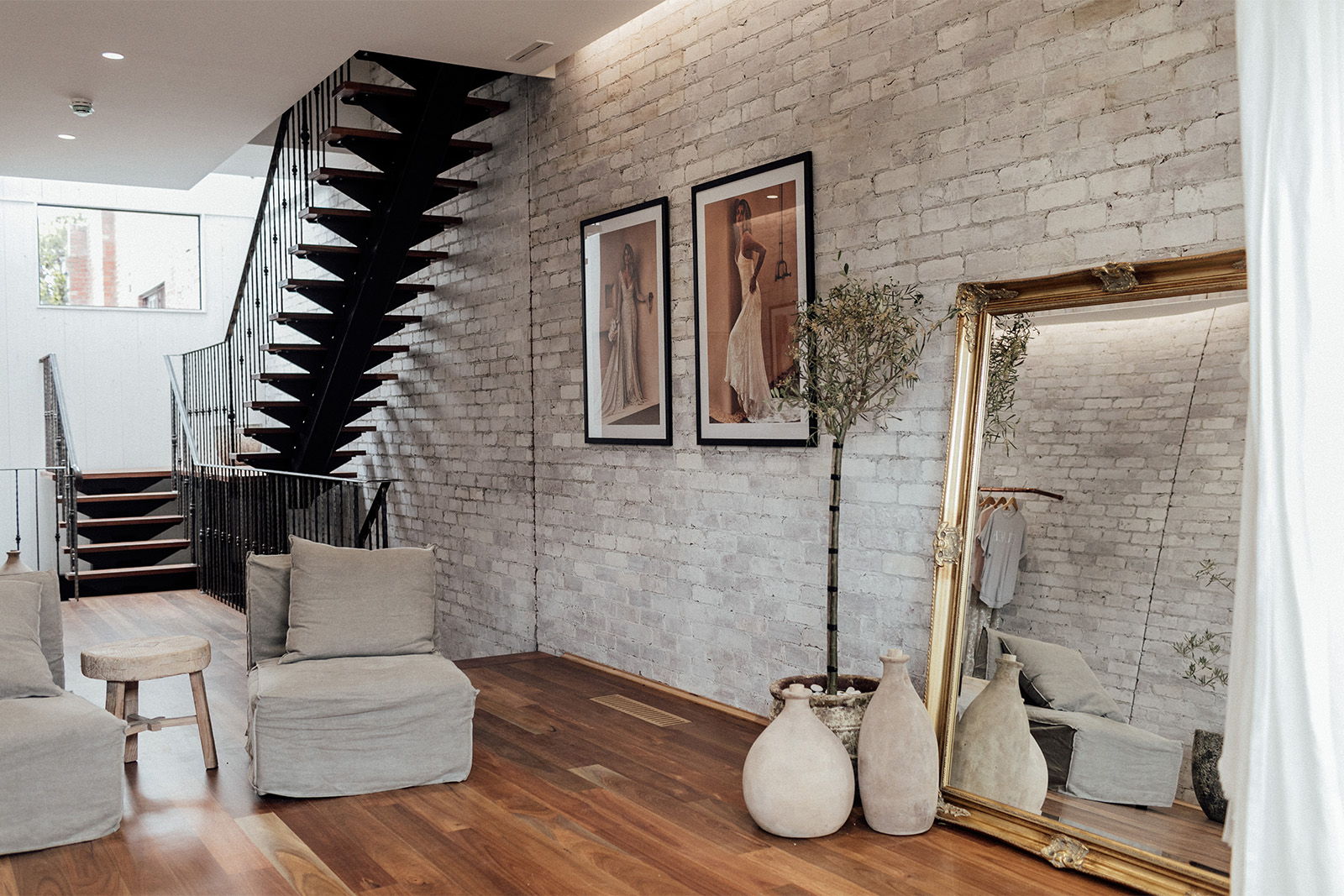 Modern interior with staircase, artwork, mirror, and cozy seating.