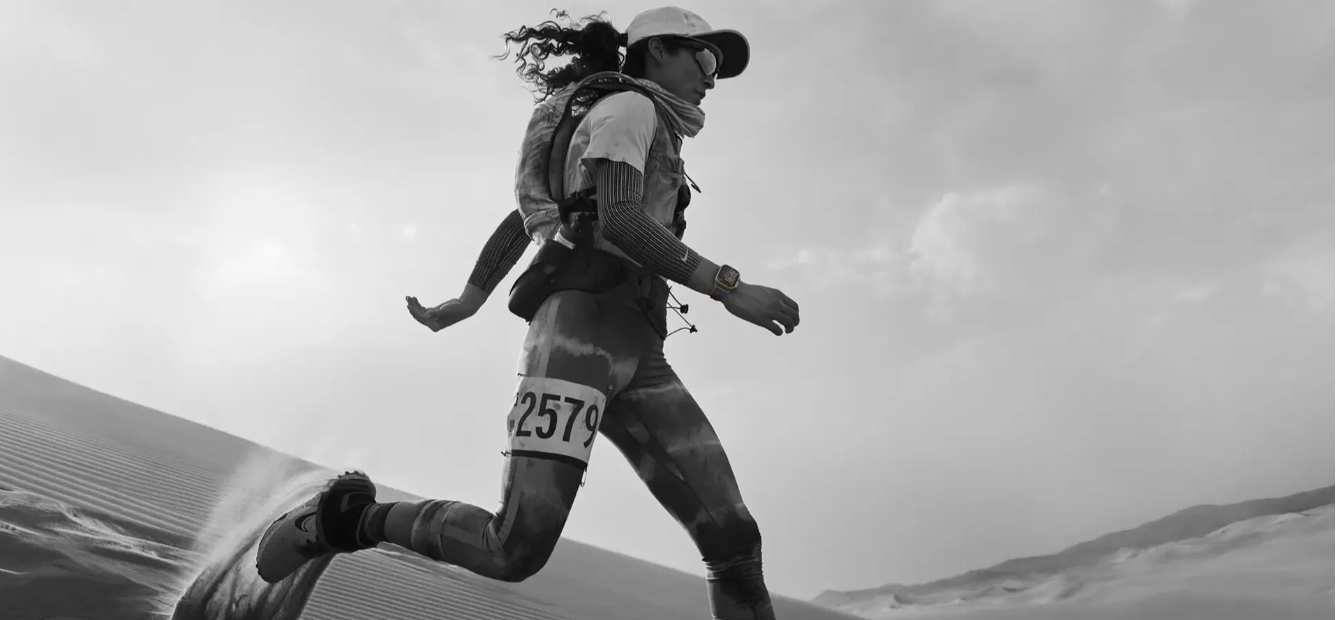 A woman running an ultra marathon in the desert with an Apple Watch Ultra
