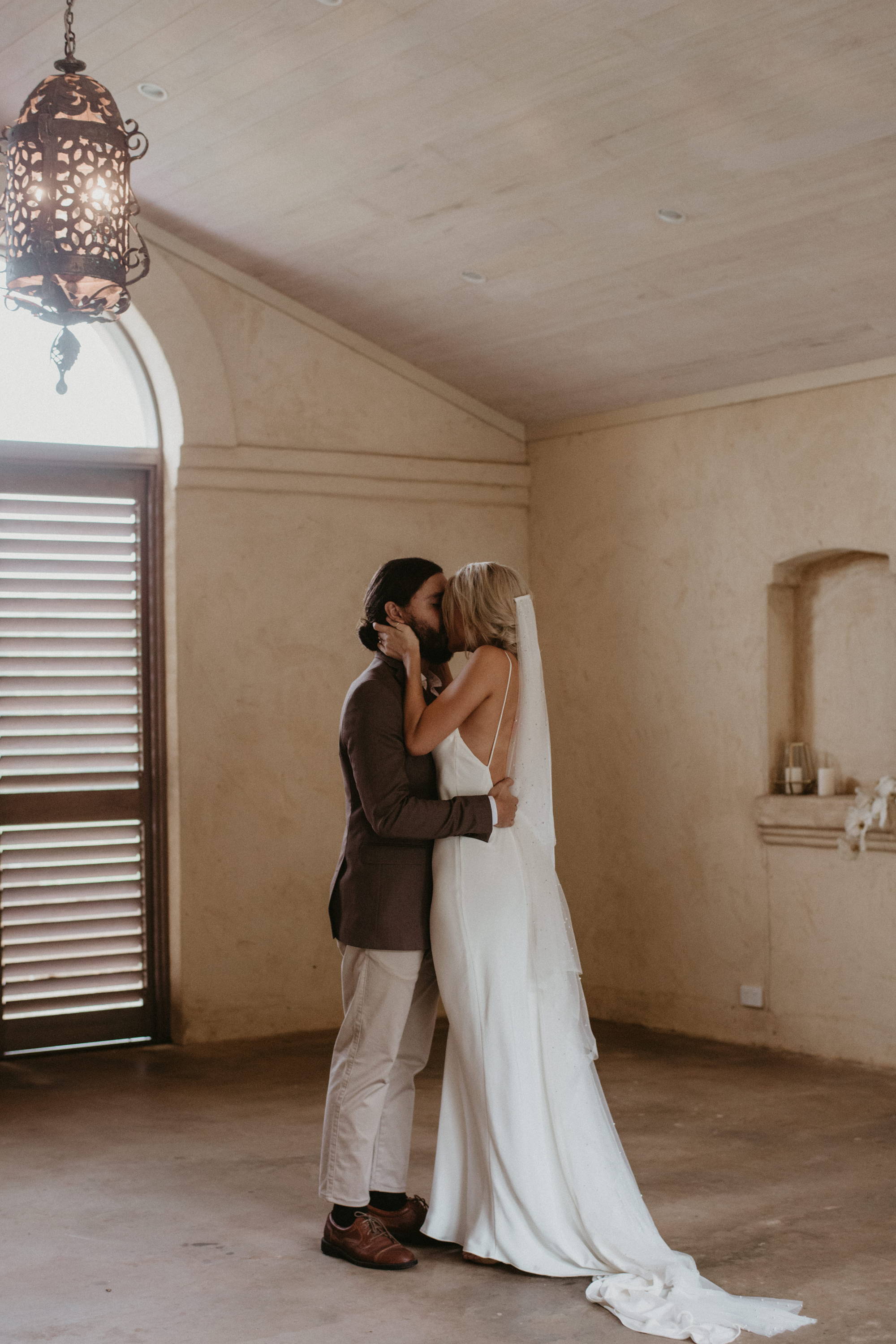 Bride and groom kissing in terracotta room 