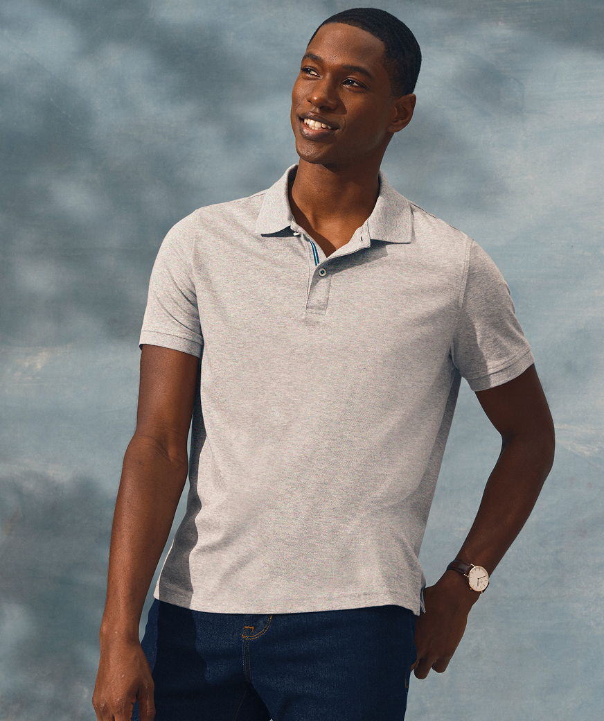 Smiling man in a gray polo shirt against a cloudy background.