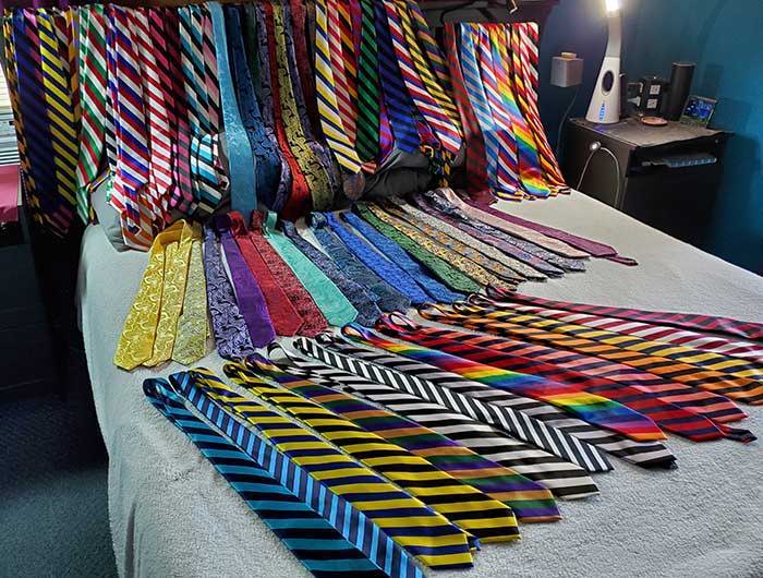 Large collection of neckties displayed on a bed