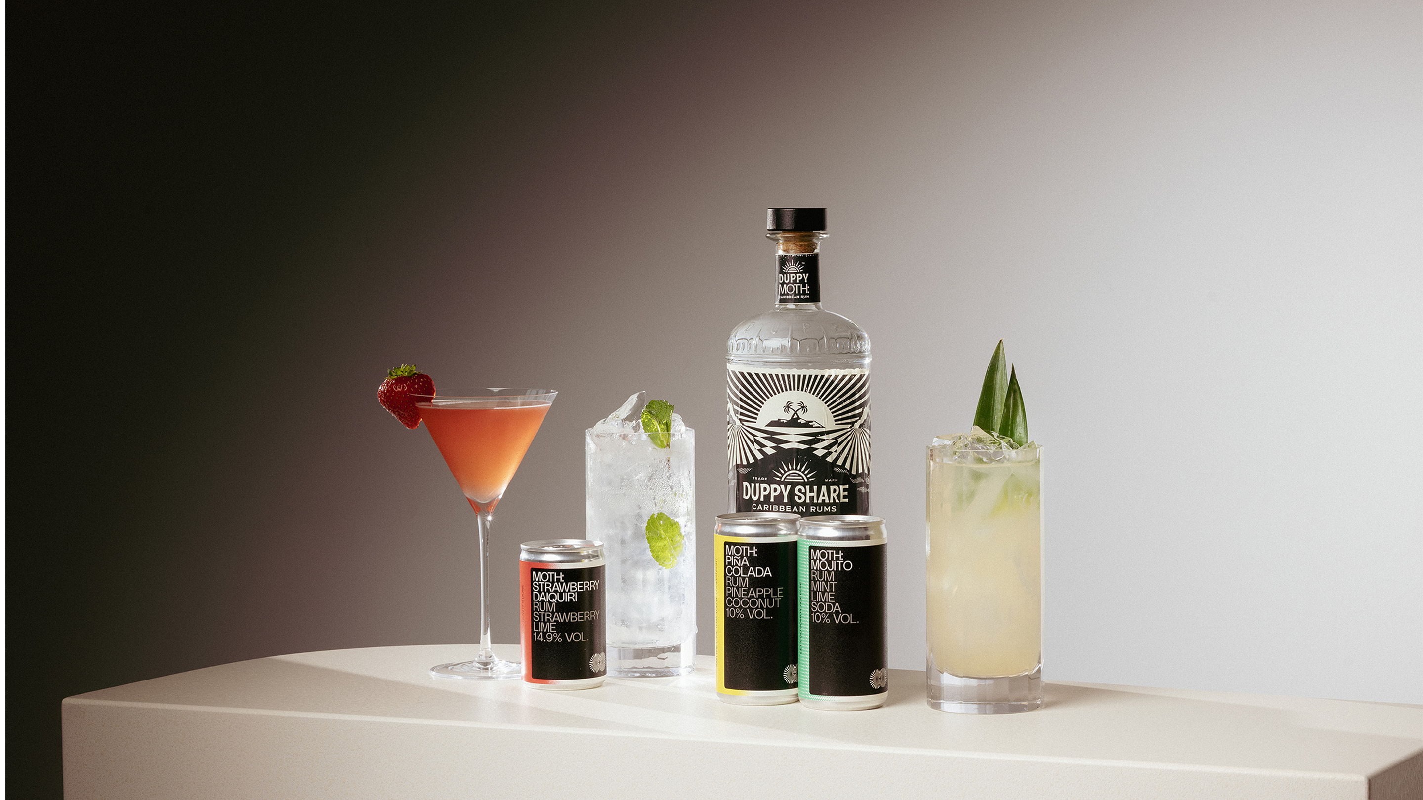 Four cocktails and a bottle of liquor on a table.