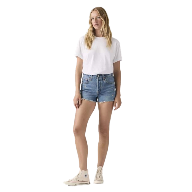 A woman in a white t-shirt and denim shorts standing.