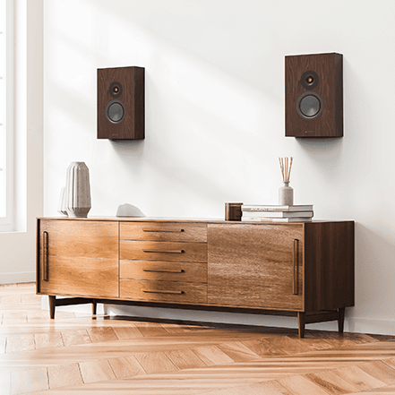 Modern living room with wooden sideboard and wall-mounted speakers.