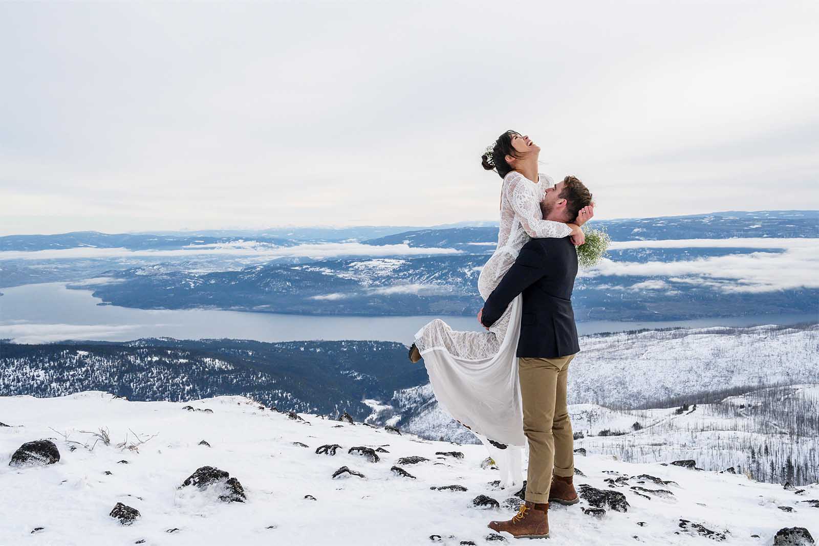 Groom, lifting the bride in the air. Winter wedding celebration in the snowy mountains. 