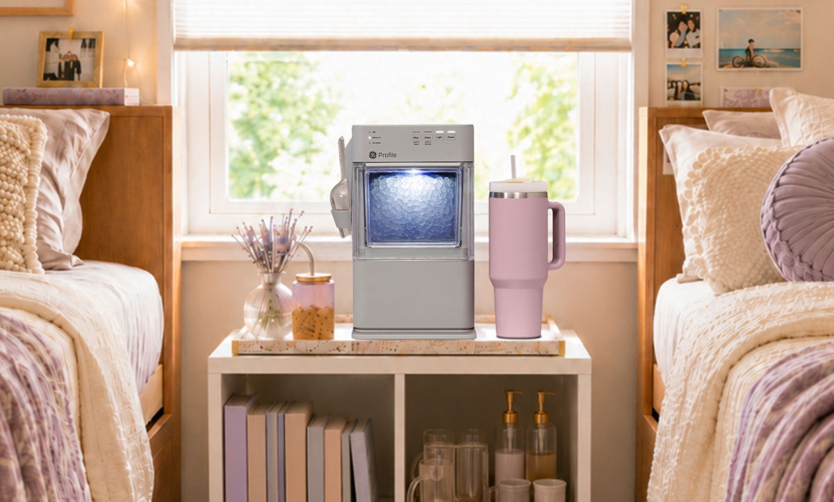 A coffee maker on a nightstand between two beds in a cozy room.