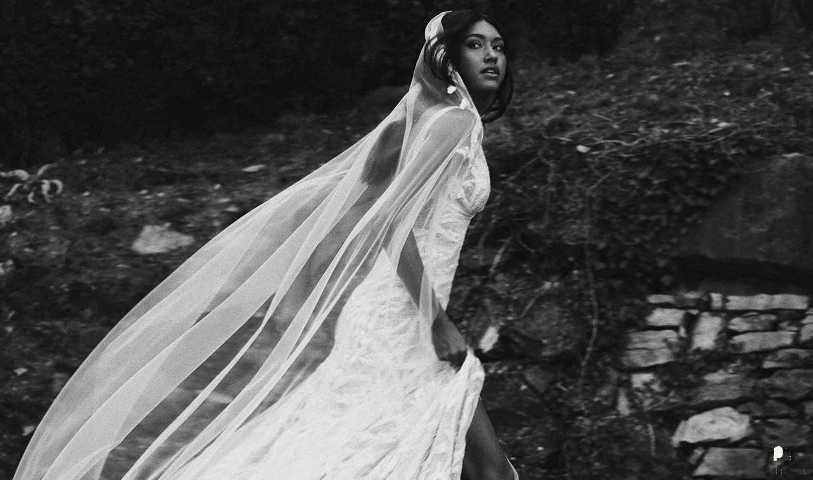 Model in motion in Solstice Gown and Solstice Veil with rock wall in background