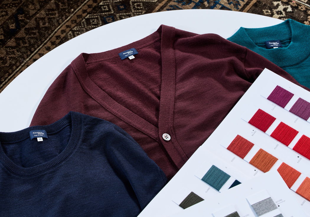 Three sweaters and a color swatch card on a table.