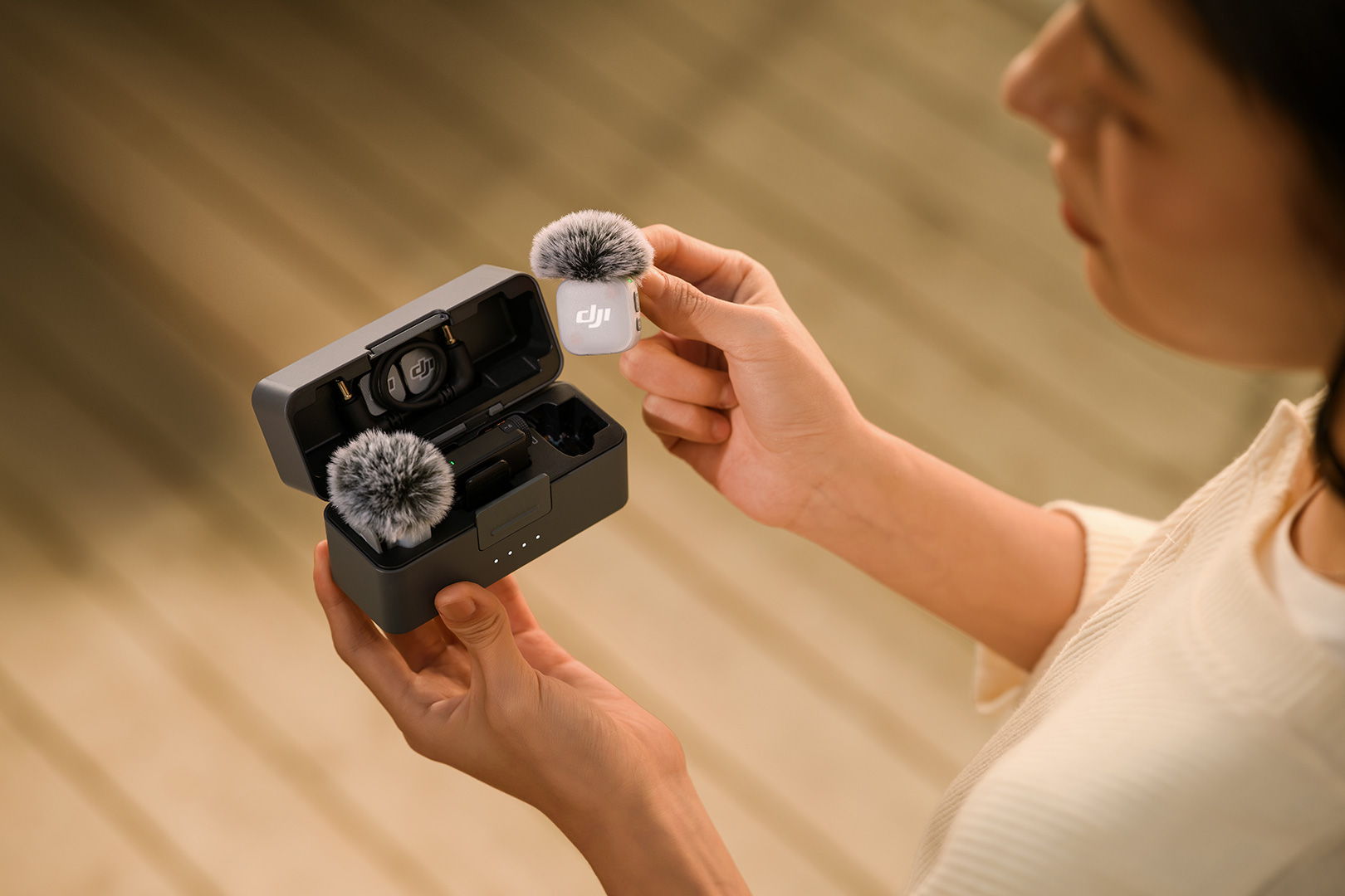A person takes a DJI Mic Mini 2 transmitter out of the charging case