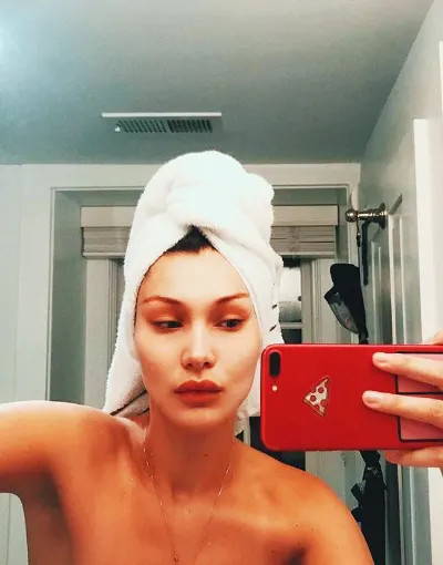 Bella Hadid with a head towel on taking a selfie in the mirror