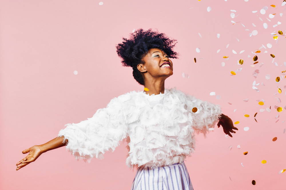 happy woman smiling|confetti|pink background|steps to achieve your goals