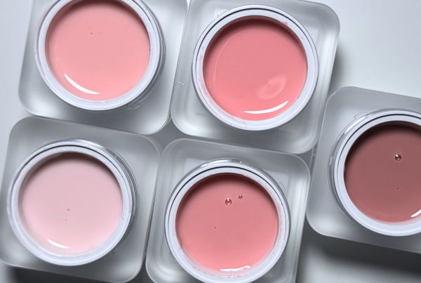 Five containers of pastel-colored nail polish arranged on a white surface.