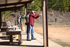 People practicing shooting at an outdoor range on a sunny day.