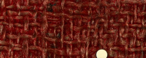 Close-up of textured reddish-brown fabric with a circular white button.