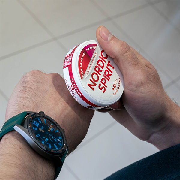A hand holding a can of Nordic Spirit with a watch on the wrist.