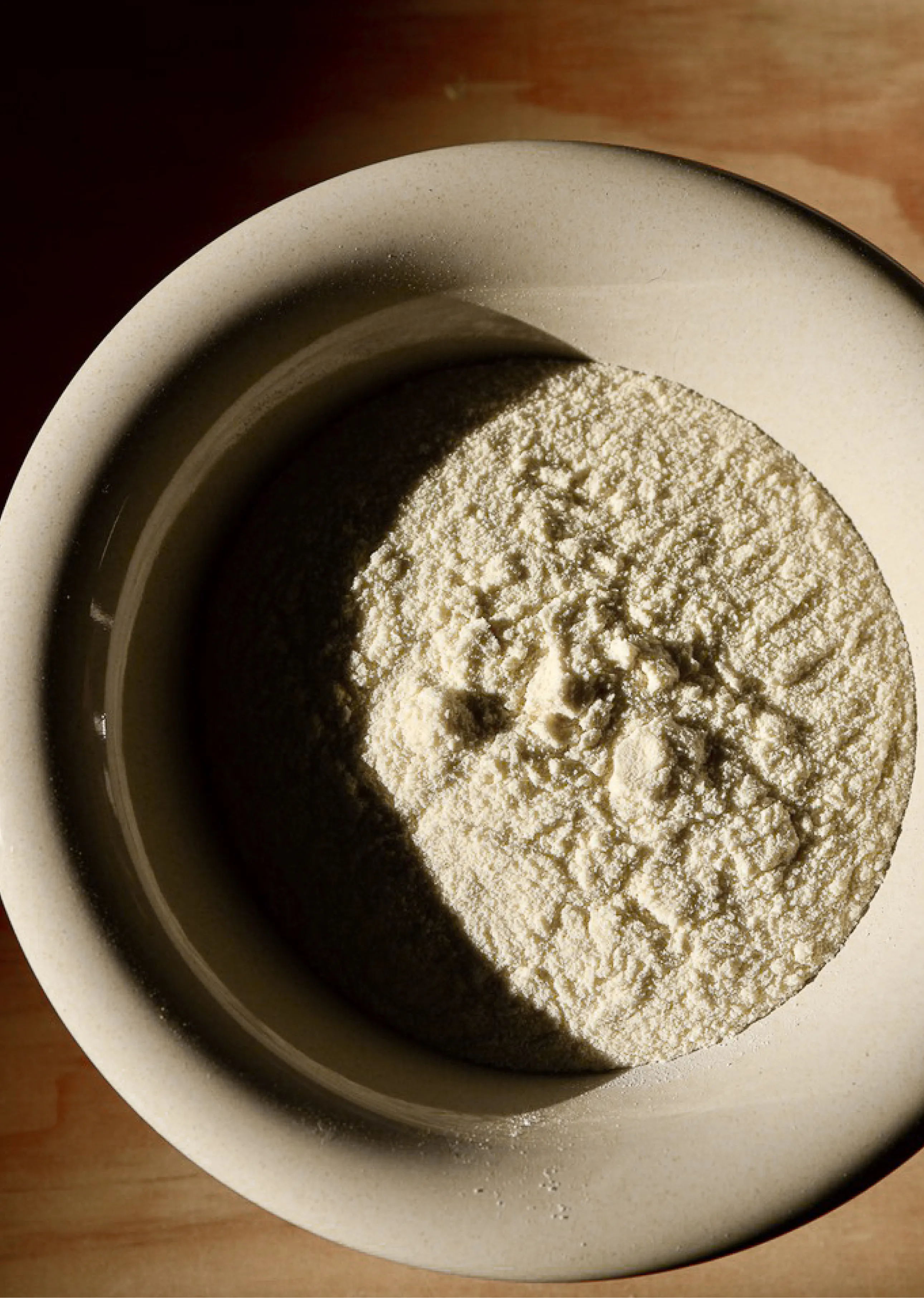 A bowl of flour with shadows and light patterns.
