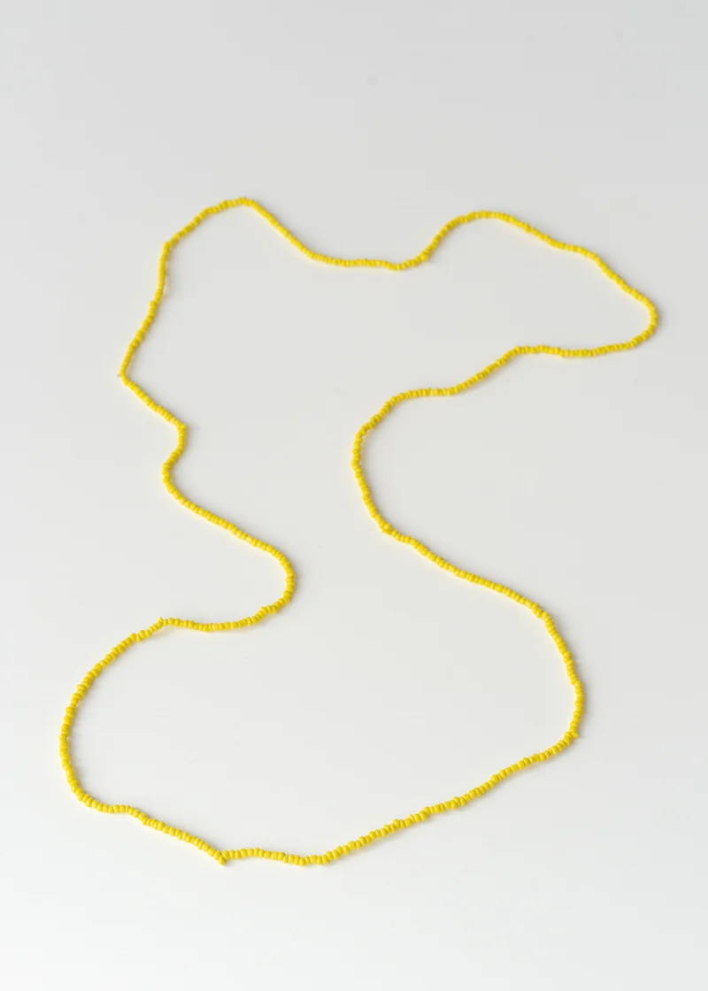 A yellow small beaded necklace on a white background