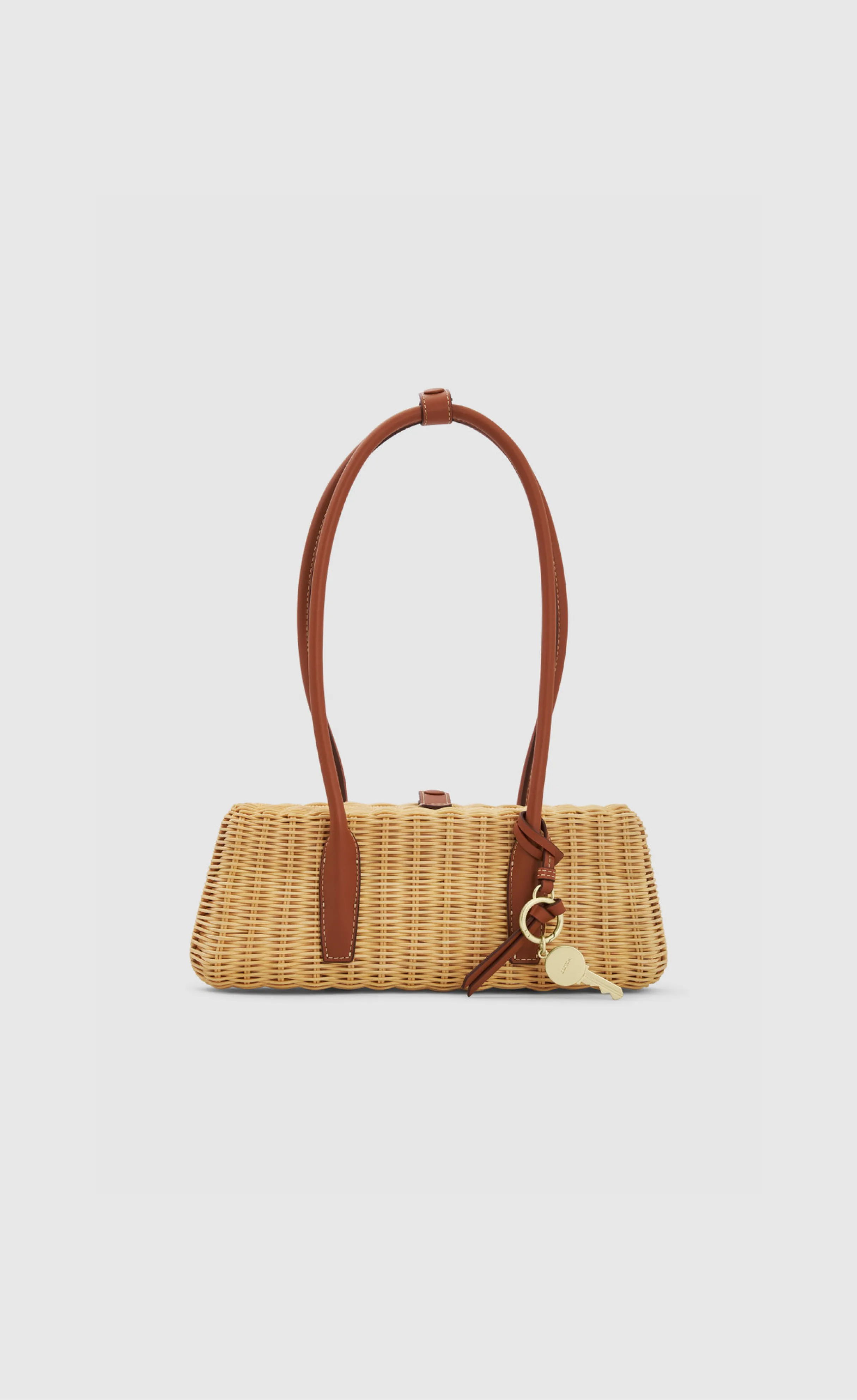 A woven handbag with a brown handle and charm.