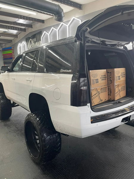 Indoor rear three-quarter view of Addison's Tahoe with the hatch open and HornBlasters boxes in the cargo area, install photo 4