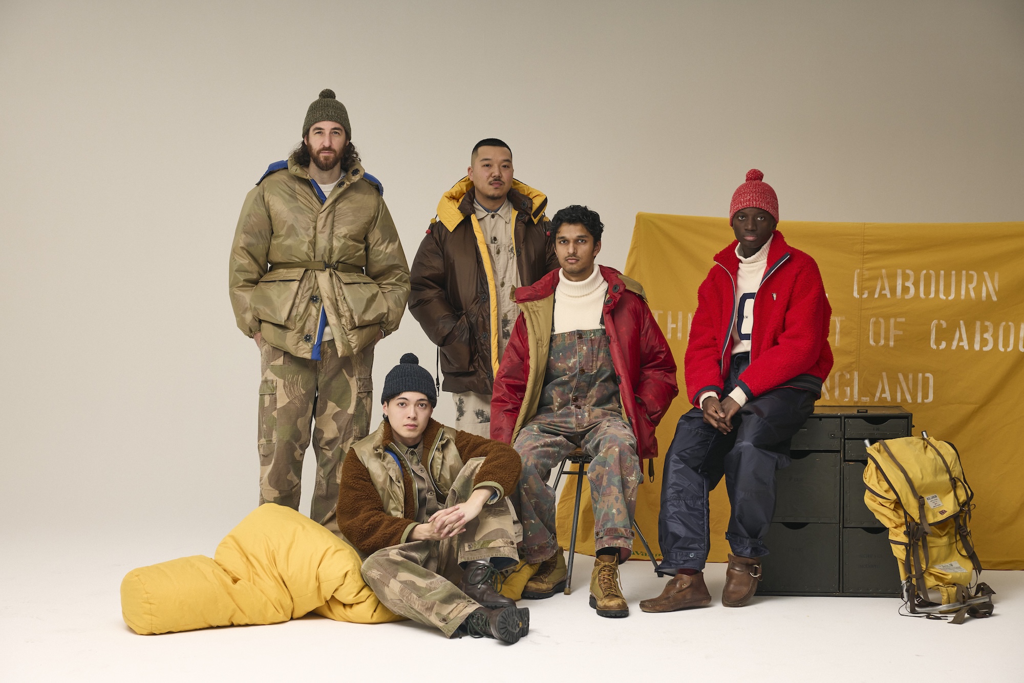 Five people in stylish winter clothing posing against a neutral background.