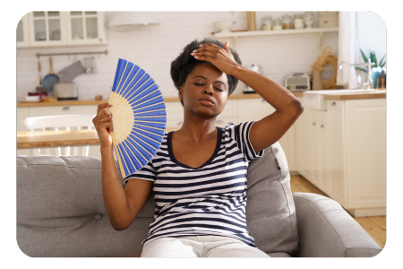 Common symptoms of menopause woman fanning herself sat down 