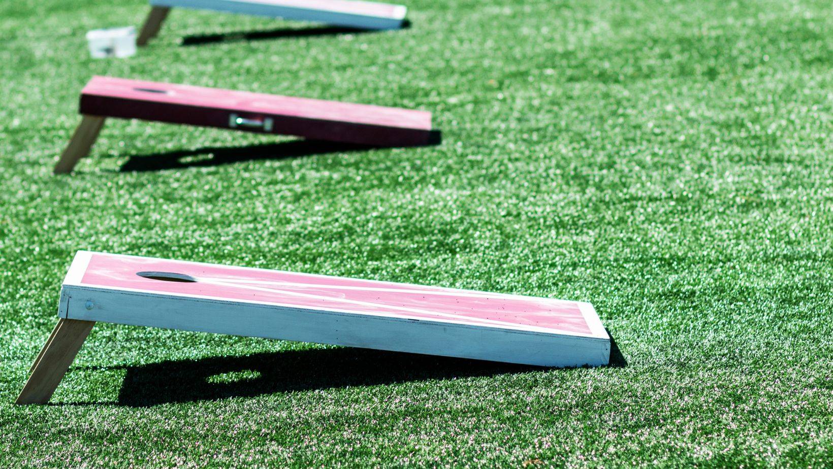 Three homemade cornhole games on turf field