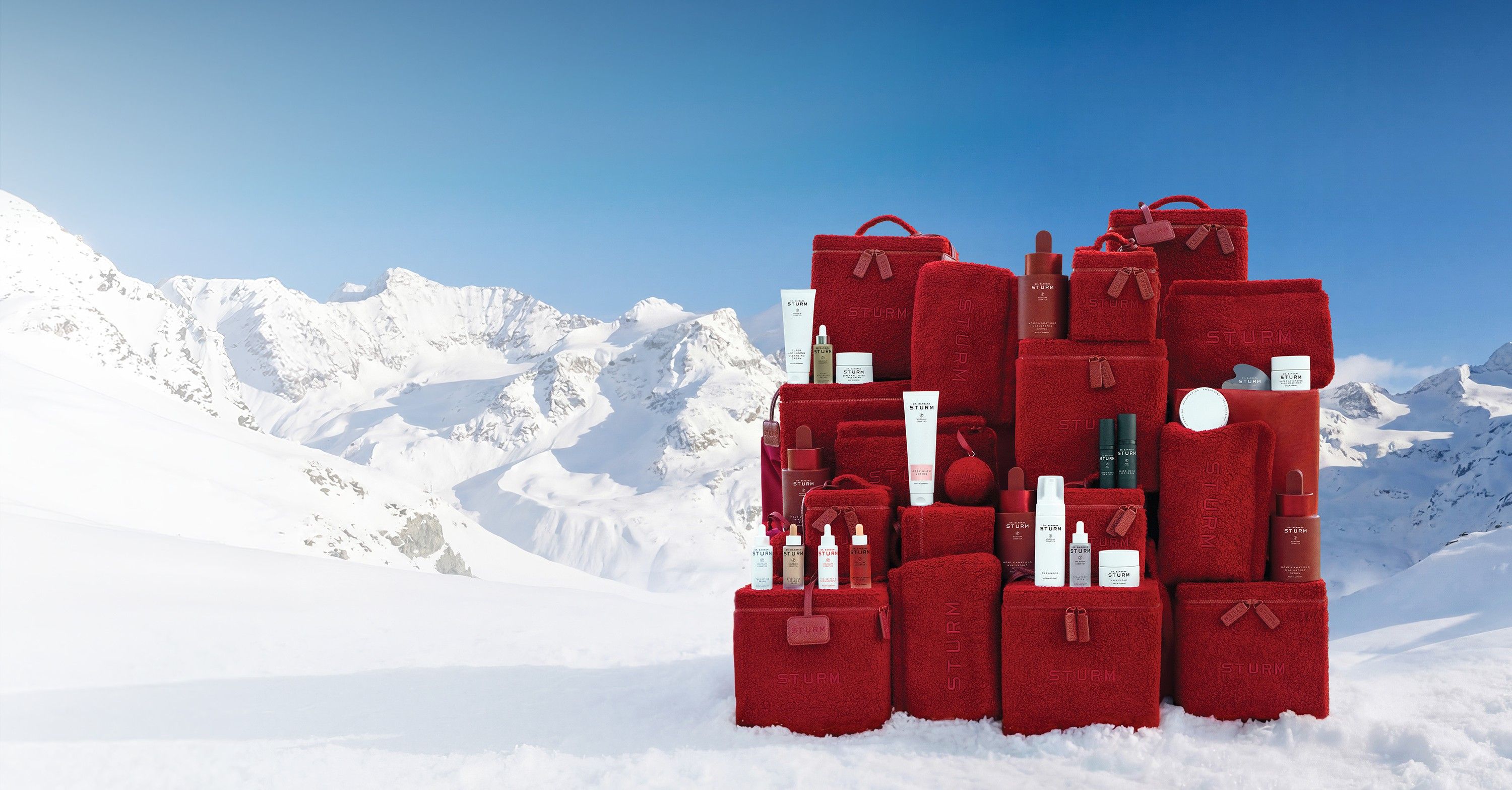 Red bags and skincare products in a snowy mountain landscape.