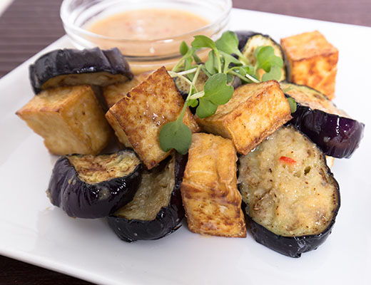 A plate of fried tofu and eggplant with dipping sauce.