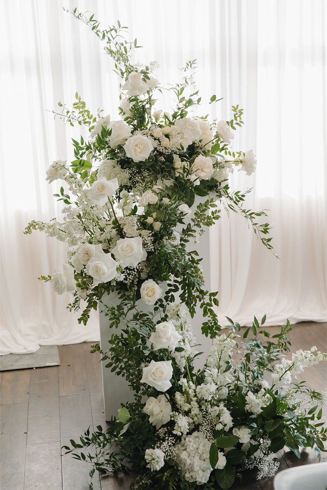 A floral arrangement with white flowers and greenery against a light backdrop.