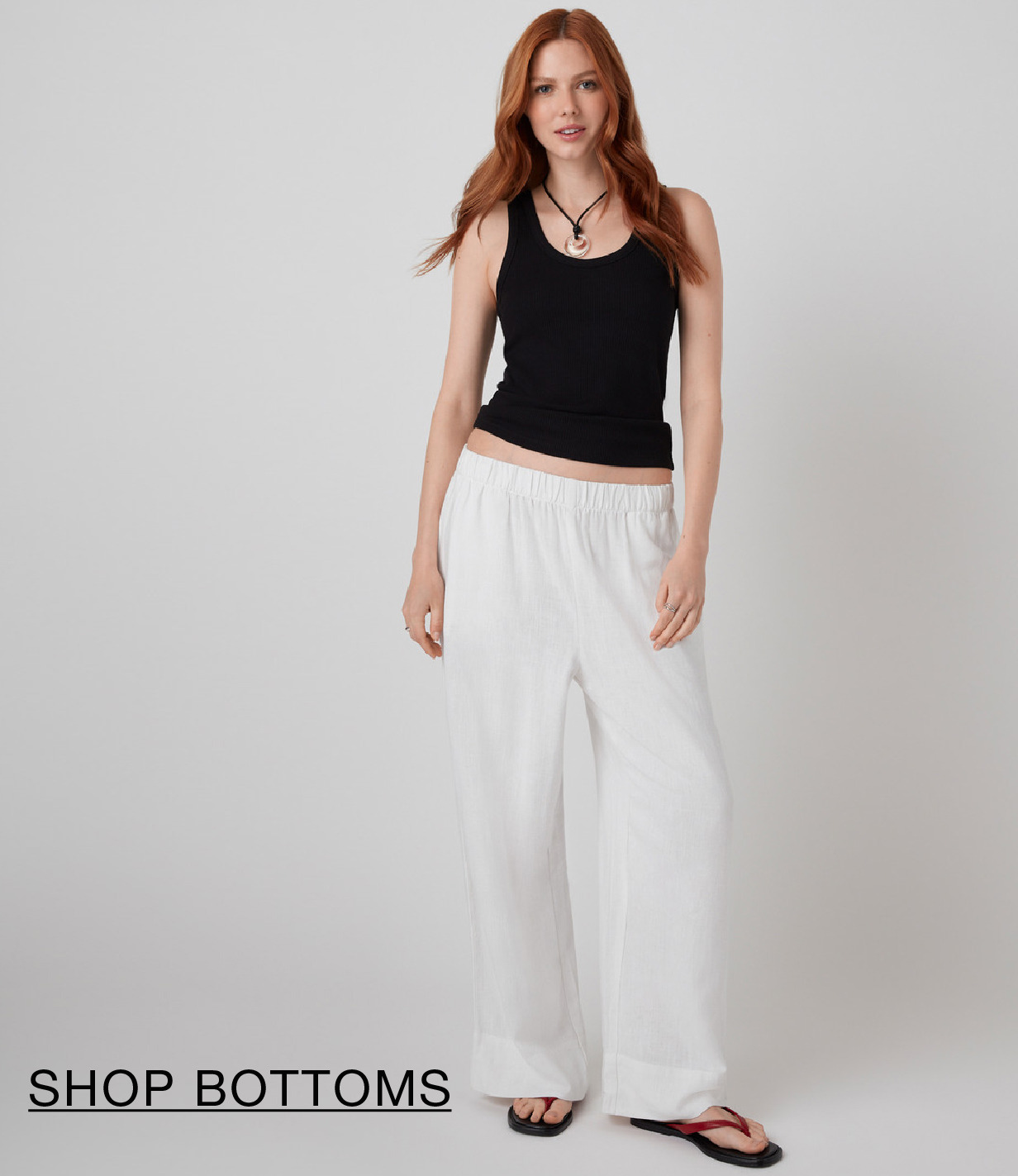 Model wearing a black tank top and white wide-leg pants.